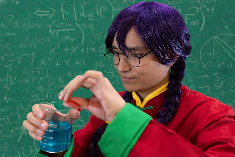 Pouring a red liquid from a test tube into a beaker filled with blue liquid.